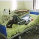 Travel Medicine - Patient in private hospital, notice the sink is not working behind him and family provided sheets and drinks.